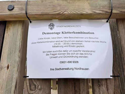 Bild: Es zeigt ein Hinweisschild zur bevorstehenden Demontage der Kletterkombination aus Holz. 