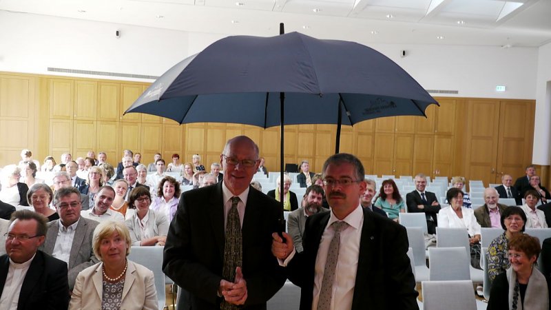 Superintendent Andreas Schwarze schenkt dem Bundespräsidenten einen Schirm, unter dem auch noch Freunde Platz finden